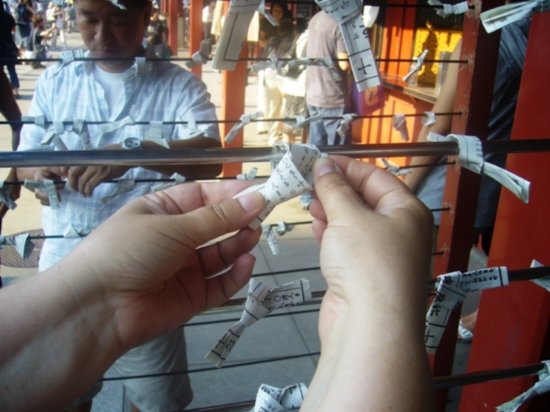 Tying Omikuji strip to 'tree'